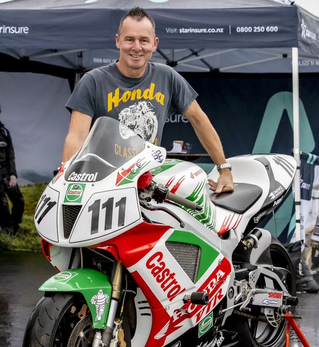 Aaron Slight smiling beside a white, red and green Castrol Honda RVF number 111